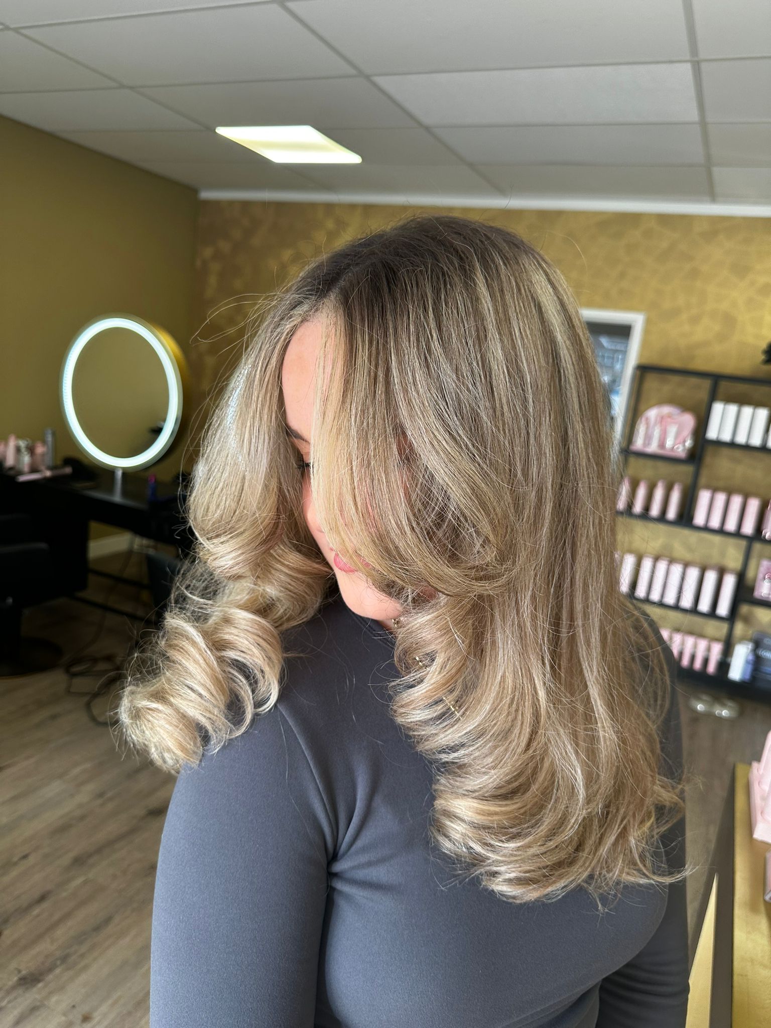Gelaagd blond haar met naar buiten vallende krullen in de salon