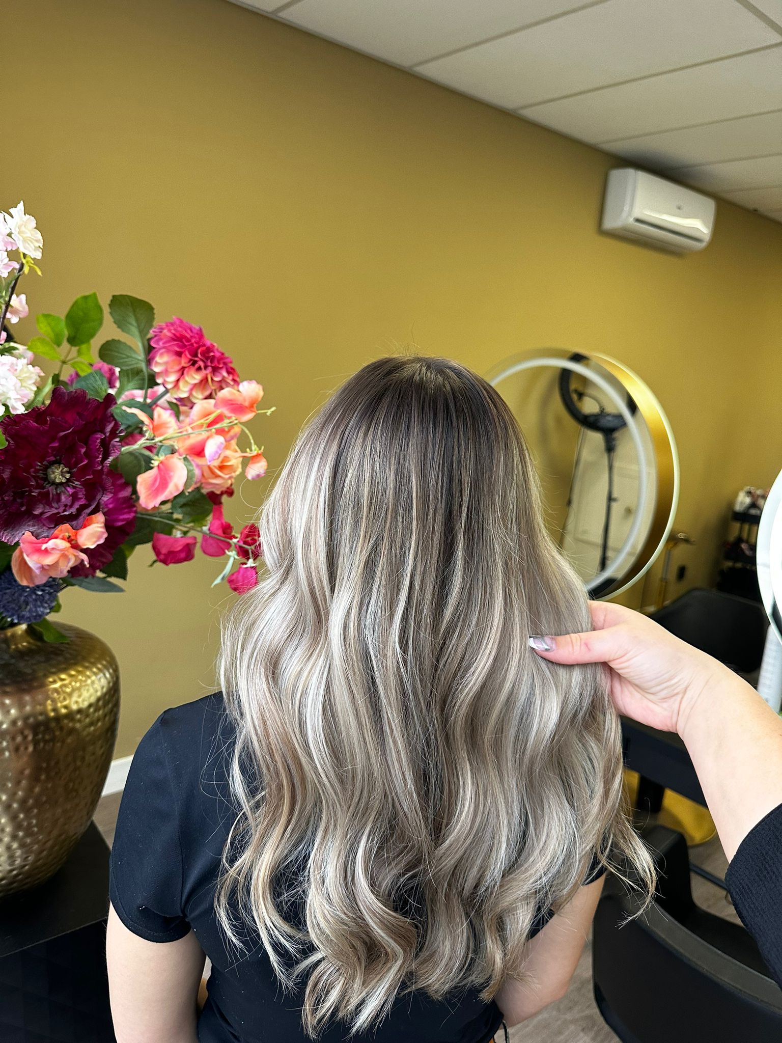 Zilverblonde golven bij Salon Hairgoals, met bloemendecoratie op de achtergrond